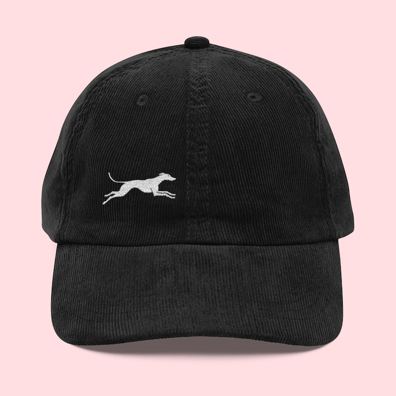 May include: Black corduroy baseball cap with a white embroidered running dog design. The cap has a curved brim and an adjustable strap at the back. A stylish accessory for casual wear.