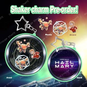 May include: Shaker charm pre-order! The image displays two circular charms with a star-shaped keychain. One charm features a cartoon character named Rocky and another with Grace. The back of the charm says "Project Hail Mary".