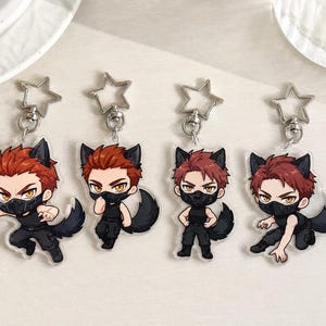 May include: Four acrylic keychains featuring a cartoon character with red hair, wolf ears, and a black tail, wearing a black sleeveless top, black pants, and a black face mask. Each charm is attached to a silver-colored star-shaped metal clasp.