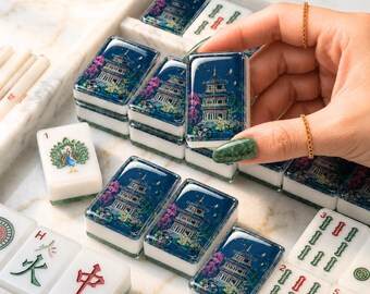 May include: A set of rectangular mahjong tiles with white bases. Several tiles feature a detailed blue illustration of a multi-story pagoda surrounded by pink and green foliage. Other tiles display green peacock motifs, red Chinese characters, and green bamboo patterns.