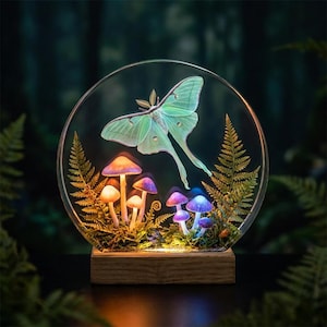 May include: A decorative illuminated glass orb featuring a large, light green moth and several colorful mushrooms. The mushrooms have purple and orange caps. The orb is set on a wooden base, creating a whimsical, nature-inspired art piece.
