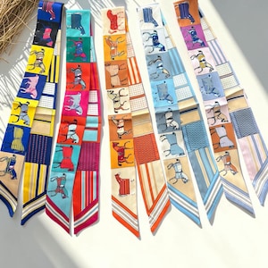 Puede incluir: Una colección de coloridas bufandas de seda con estampados ecuestres y geométricos. Cada bufanda presenta una combinación única de colores, incluyendo azul, amarillo, rojo y naranja. Las bufandas están dispuestas en forma de abanico.