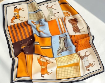 May include: A square silk scarf featuring a grid pattern of orange, light blue, and cream panels. The design includes illustrations of horses wearing blankets, striped sections, and a black border. The scarf has a smooth, reflective finish.