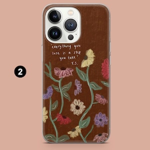 May include: A brown phone case with a floral design and the quote "everything you lose is a step you take" by T.S. The case features colorful flowers in shades of yellow, pink, purple, and red.