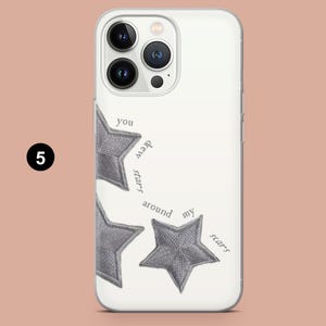 May include: White phone case with a design featuring three gray embroidered stars and the text "you drew stars around my scars". The case has a clear border and covers the back and sides of the phone.