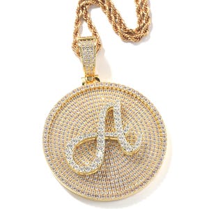 May include: Gold-toned pendant necklace featuring a large, round pendant with a sparkling 'A' initial. The pendant is encrusted with small, clear gemstones, and hangs from a matching gold rope chain. The jewelry is set against a white background.