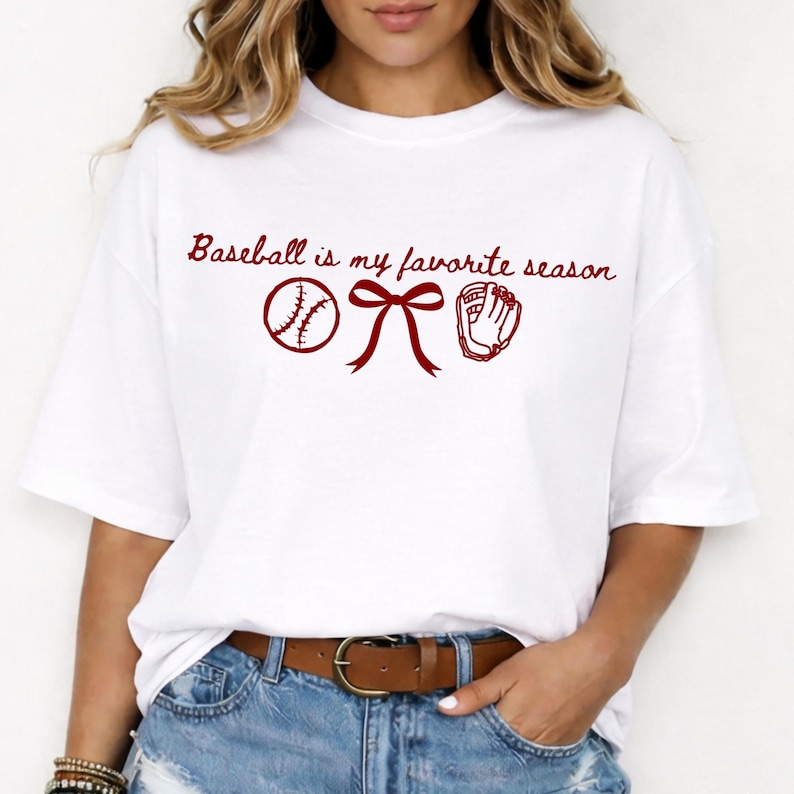 May include: White t-shirt with the text "Baseball is my favorite season" in a burgundy script. The design includes a baseball, a bow, and a baseball glove in burgundy. The shirt is a casual, everyday wear item.