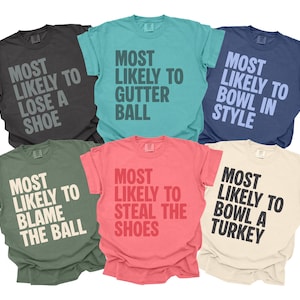 May include: Six short-sleeved t-shirts in a range of colours: charcoal, teal, navy, olive green, coral, and cream. Each shirt has a humorous phrase in capital letters, such as "MOST LIKELY TO LOSE A SHOE".