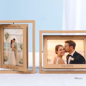 Op de afbeelding: Twee houten fotolijsten met trouwfoto's. Eén lijst heeft de tekst "Our Wedding Day" en "06.15.2025". De andere lijst heeft de tekst "Sophia & Daniel" en "Est. 2025". De lijsten staan op een wit oppervlak.