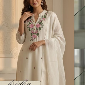 K&ouml;nnte beinhalten: Cremefarbenes besticktes Kurta-Set mit passendem Dupatta. Das Kurta hat einen Stehkragen und florale Stickereien in Rosa und Gr&uuml;n. Der Text "kridha FASHION" ist unten sichtbar.