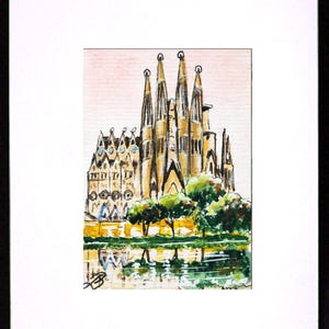 Puede incluir: Pintura a la acuarela de la Sagrada Fam&iacute;lia en Barcelona, Espa&ntilde;a. La obra representa la bas&iacute;lica con sus intrincadas agujas, &aacute;rboles y un reflejo en el agua. La pintura est&aacute; enmarcada en un passe-partout blanco y un marco negro.