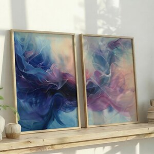 May include: Two framed abstract art prints with swirling blue, purple, and pink colors. The artwork is displayed on a wooden shelf with decorative items and plants. The frames have a natural wood finish.