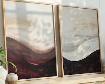 May include: Two framed abstract paintings with a wave-like design in shades of burgundy, beige, and white. The artwork is displayed on a wooden shelf with decorative items and plants. The frames are made of light-colored wood.