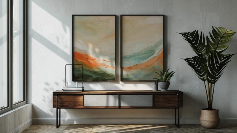 May include: Two framed abstract artworks with orange, green, and beige hues are displayed above a dark wood cabinet. A potted plant and decorative items sit on the cabinet. A large potted plant with green leaves is on the right.