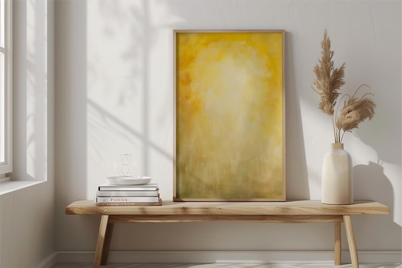 Pode incluir: Uma impress&atilde;o de arte abstrata emoldurada com uma paleta de cores amarelas e verdes. A obra de arte &eacute; exibida em um banco de madeira, junto com um vaso com plantas secas, livros e um prato decorativo. A cena &eacute; iluminada por luz natural.