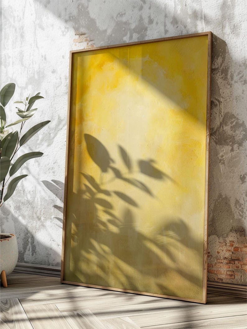 Pode incluir: Uma impress&atilde;o de arte emoldurada com um fundo amarelo e dourado. A obra apresenta um fundo texturizado com sombras de folhas. A moldura &eacute; de madeira clara. A impress&atilde;o est&aacute; encostada numa parede texturizada.