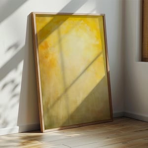 Pode incluir: Uma impress&atilde;o de arte abstrata emoldurada com uma paleta de cores amarelo e laranja. A obra de arte &eacute; exibida em uma moldura de madeira clara e est&aacute; encostada em uma parede branca. O quarto tem um ch&atilde;o de madeira e luz natural.