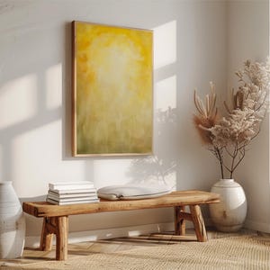 Pode incluir: Uma cena interior acolhedora com um banco de madeira, livros e uma almofada. Uma grande pintura abstrata em tons de amarelo e verde est&aacute; pendurada na parede. Um vaso com flores secas e um vaso branco grande completam a decora&ccedil;&atilde;o.