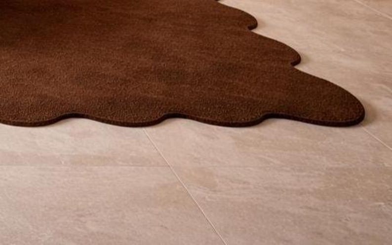 Luxury solid brown area rug with soft wavy edges placed in a modern minimalist living space, contemporary carpet on marble floor with wooden table and neutral walls, elegant modern rug for living room bedroom and hallway décor