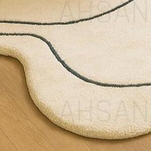 Modern irregular shaped cream rug with abstract wavy edge design, minimalist black and orange line art pattern, contemporary carpet for living room or bedroom décor.