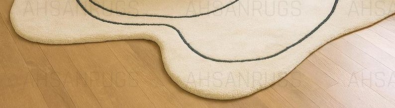Modern irregular shaped cream rug with abstract wavy edge design, minimalist black and orange line art pattern, contemporary carpet for living room or bedroom décor.