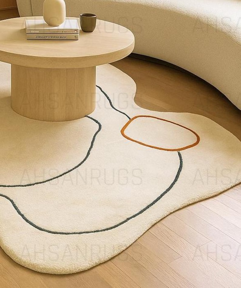 Modern irregular shaped cream rug with abstract wavy edge design, minimalist black and orange line art pattern, contemporary carpet for living room or bedroom décor.