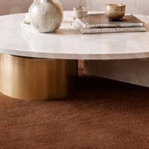 Luxury solid brown area rug with soft wavy edges placed in a modern minimalist living space, contemporary carpet on marble floor with wooden table and neutral walls, elegant modern rug for living room bedroom and hallway décor