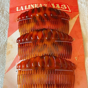 May include: Three brown tortoiseshell hair combs with a scalloped top edge, arranged vertically on a red and white patterned cardboard backing card that features the text LA LINEA 3 and L13 printed in white at the top of the packaging.