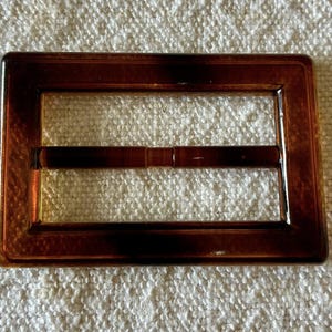 Pode incluir: Um conjunto de três canecas de cerâmica com acabamento fosco e salpicado. As canecas são em tons de creme, cinza claro e cinza escuro. Cada caneca tem um design simples e minimalista e uma alça arredondada.