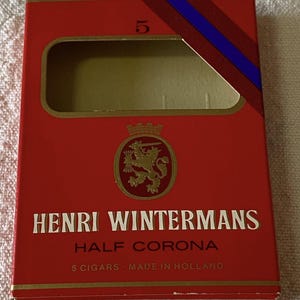 May include: A red Henri Wintermans Half Corona cigar box with gold trim and a gold emblem. The box has a cut-out window and a blue and red ribbon. The text "5 Cigars - Made in Holland" is visible.