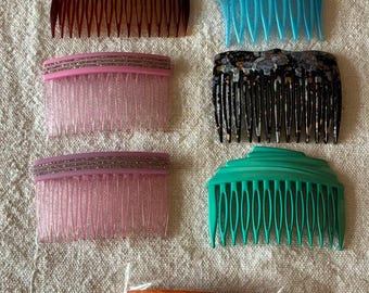 Può includere: Una collezione di nove pettini per capelli in vari colori e finiture. Il set include due pettini marrone scuro, uno color lavanda, uno blu, due rosa con fasce glitterate, uno nero con macchie dorate, uno turchese e uno arancione in una busta di plastica.