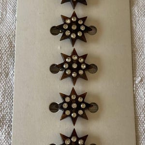 Pode incluir: Seis grampos de cabelo em forma de estrela com um design de tartaruga marrom escuro e detalhes de strass transparentes. Os grampos são presos a um cartão branco com o texto "moda para el pelo".