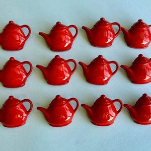 May include: A collection of twelve small, glossy red teapots arranged in a grid of three rows and four columns. Each teapot features a rounded body, a curved spout, a small handle, and a lid, all rendered in a uniform, vibrant red finish.