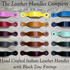 May include: A selection of colourful leather handles with black zinc fittings. The handles are in various colours, including pink, yellow, blue, red, brown, black, and green. The text "The Leather Handles Company" and "Hand Crafted Italian Leather Handles with Black Zinc Fittings" are visible.