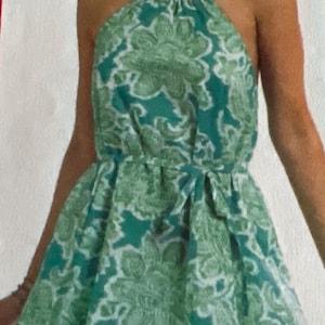 May include: A green halter top with a floral print and a matching headband. The top has a tie at the waist and a flowing skirt.