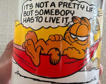 McDonalds Glass Mug Garfield Jim Davis Garfield in Hammock 1978 Clear mug with handle yellow and red colors 3.25 inches tall w 3” diameter