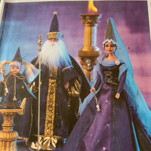 May include: A McCall's Crafts pattern for making doll clothes. The pattern includes three outfits: a purple gown with a white trim, a blue and gold robe, and a black and blue outfit with a white collar. The pattern also includes instructions for making a wand and a crown.