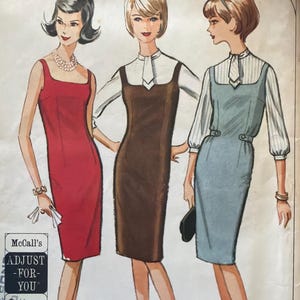 May include: Vintage McCall's sewing pattern featuring three illustrated women in dresses. The dresses are a red sheath, a brown jumper over a white blouse, and a blue dress with a white striped blouse. The pattern includes the text "ADJUST -FOR-YOU".