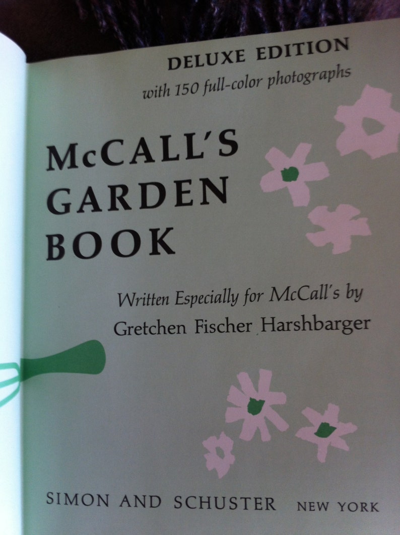 May include: A book cover with the title "McCall's Garden Book" in black text on a light green background. The book is a deluxe edition with 150 full-color photographs. The cover features pink and green stylized flowers.