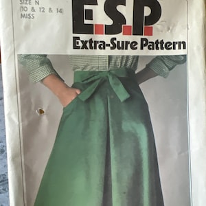 May include: Simplicity sewing pattern featuring a green skirt with a bow detail. The pattern is labeled "ESP Extra-Sure Pattern" and includes sizes for Misses. The pattern number is 8151.