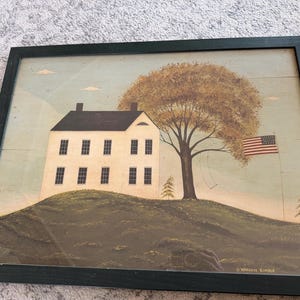 May include: Framed print of a white house on a hill with a large tree and an American flag. The artwork has a rustic, folk art style, with a dark green frame. The sky is light blue with a few clouds. The artist's name, Warren Kimble, is visible.