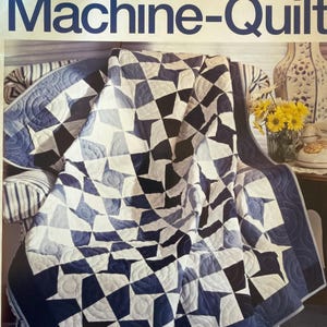 May include: A machine-quilted blanket with a geometric star pattern in shades of blue, white, and black. The quilt is draped over a striped chair. The text "Teach Yourself to Machine-Quilt" is visible at the top.
