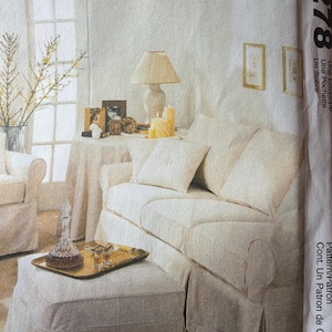 May include: A cream-colored living room scene featuring a sofa, ottoman, and armchair. A gold tray with a decanter and glasses sits on the ottoman. A table with a lamp and candles is behind the sofa. The image is from a sewing pattern.