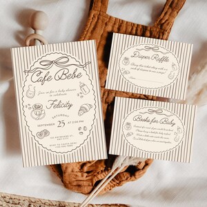 May include: Cream-colored baby shower invitations and inserts with a cafe theme. The main invitation reads "Cafe Bebe" and includes details for Felicity's shower. Inserts include "Diaper Raffle" and "Books for Baby" cards, all with a striped background.