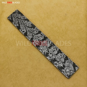 May include: A rectangular, black and white patterned blade blank with a floral design. The text "WILDFORGE BLADES" is printed on the blade. The blade is set against a tan background.
