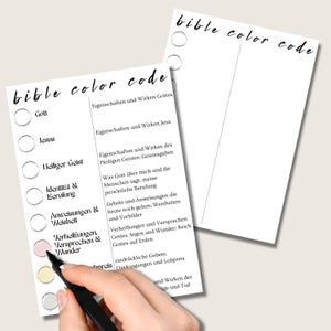 May include: Two white paper sheets with the words "bible color code" written in black script. One sheet has a list of religious terms with corresponding circles. A hand is coloring a circle pink with a black marker.