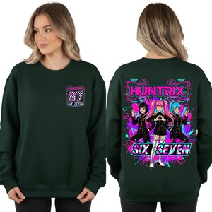 May include: Dark green sweatshirt with a graphic on the front and back. The front graphic features the text "HUNTRIX" and "SIX SEVEN" with a checkered pattern. The back graphic displays three anime-style characters and the text "HUNTRIX" and "SIX SEVEN".
