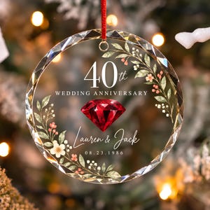 May include: A round, faceted glass ornament hanging from a red ribbon. It features the text 40th WEDDING ANNIVERSARY, a red diamond graphic, the names Lauren & Jack, and the date 08.23.1986, all surrounded by a watercolor floral wreath design.