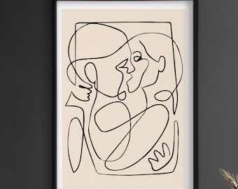 May include: Black framed art print featuring a minimalist line drawing of two figures embracing. The artwork is in black against a cream background. The print is displayed on a dark gray wall above a wooden cabinet.