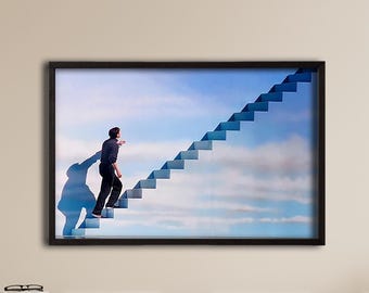 Peut inclure: Une impression encadrée représentant une personne montant un escalier menant au ciel. L'œuvre présente un ciel bleu avec des nuages, et la personne monte les escaliers. Le cadre est noir.